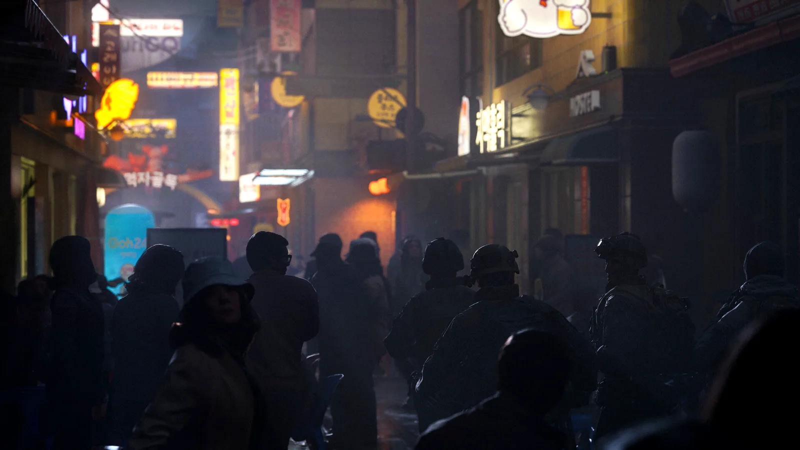 Civilians moving through a neon-lit city street at night